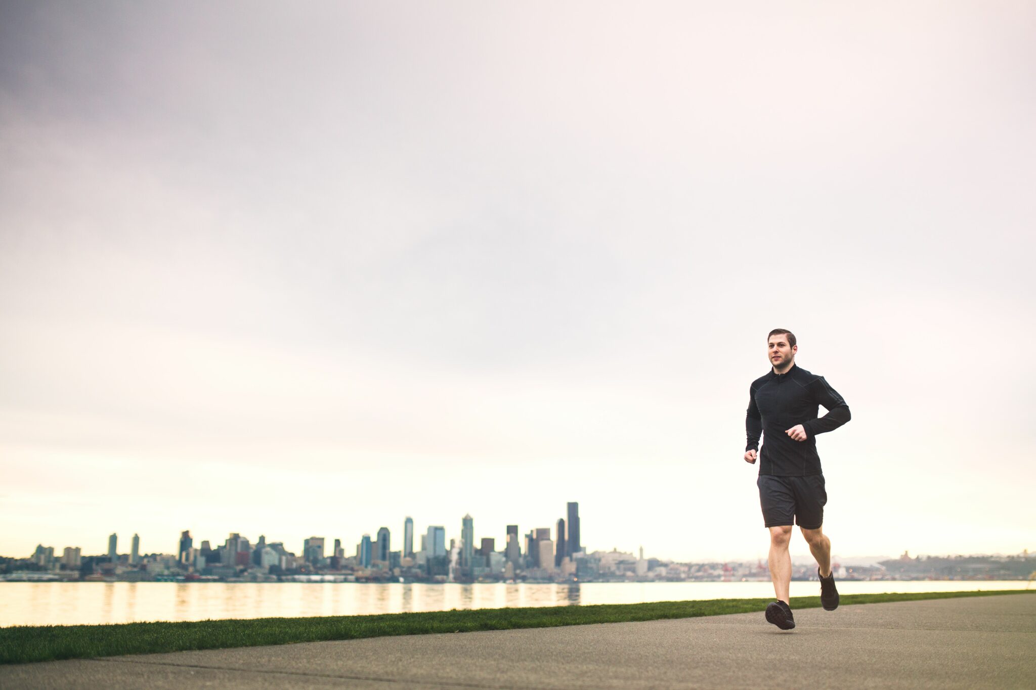 person jogging along a waterfront with visible seattle skyline